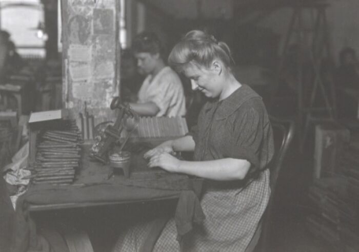 Vintage photo of American working class women operating machinery in a factory, focused on their jobs in an industrial setting.