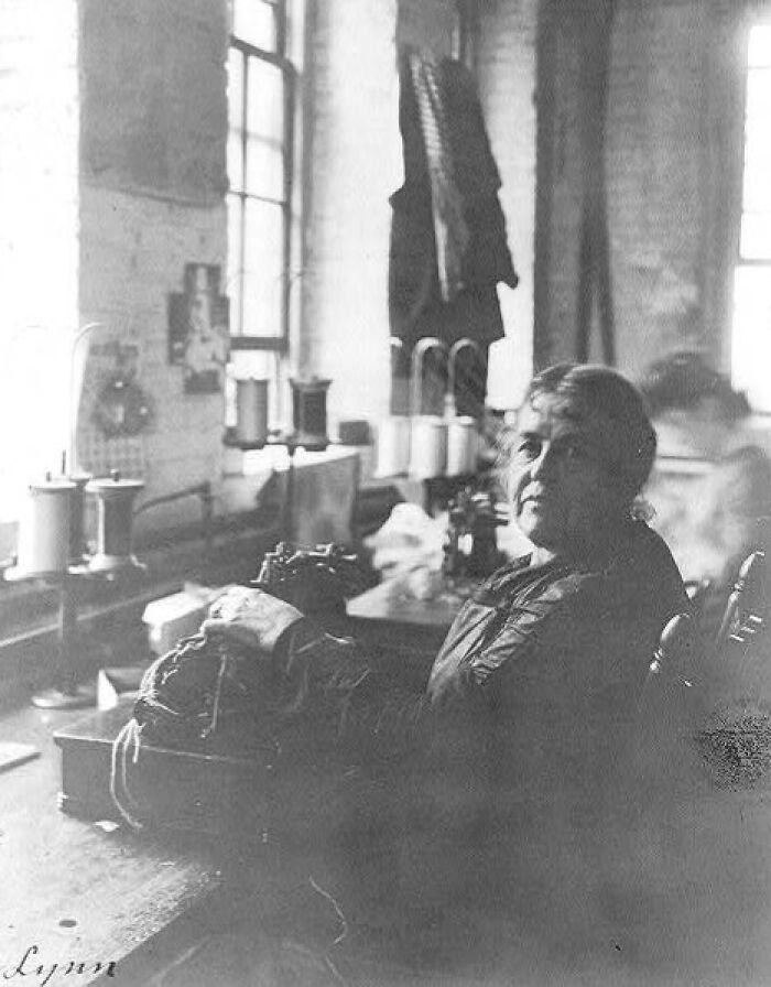 Woman vintage photo of American working class people stitching fabric in a factory, focused on her sewing job.