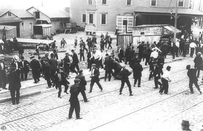 Group of American working class people gathered on a cobblestone street in the middle of their jobs vintage photo.