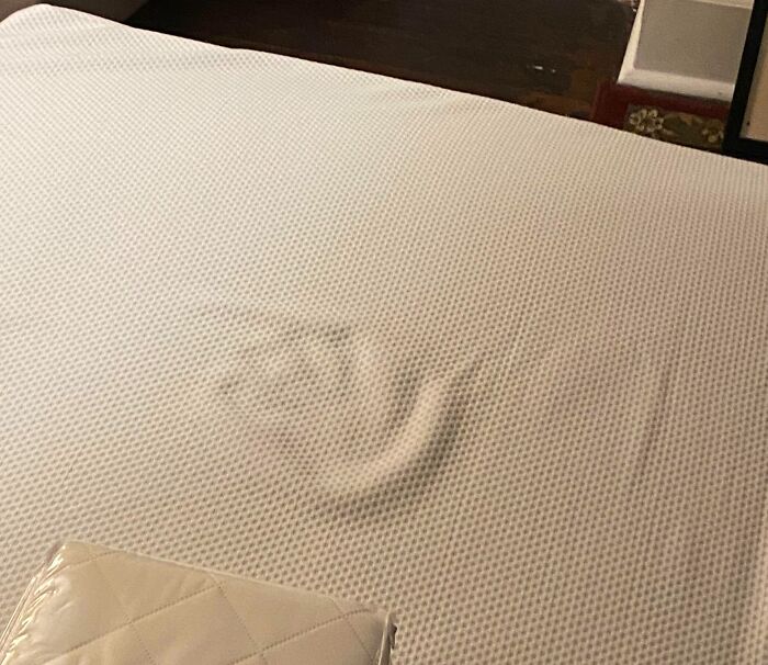 Indentation on a mattress resembling a handprint, suggesting a chilling ghost encounter in a quiet room setting.