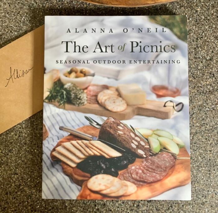 The Art of Picnics book cover featuring a charcuterie board with crackers, meats, cheese, and fruit for outdoor entertaining.