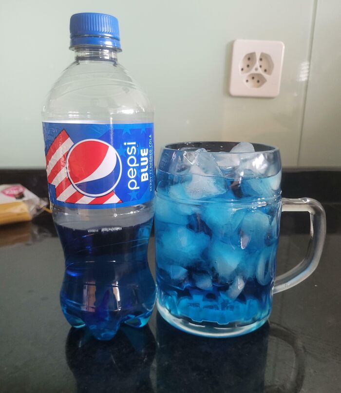 Pepsi Blue bottle and a glass filled with blue soda and ice cubes, a beloved drink that disappeared from the market.