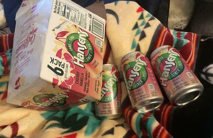 Six-pack of Hansen's Cherry Vanilla soda, a beloved discontinued food and drink, displayed on a colorful blanket.