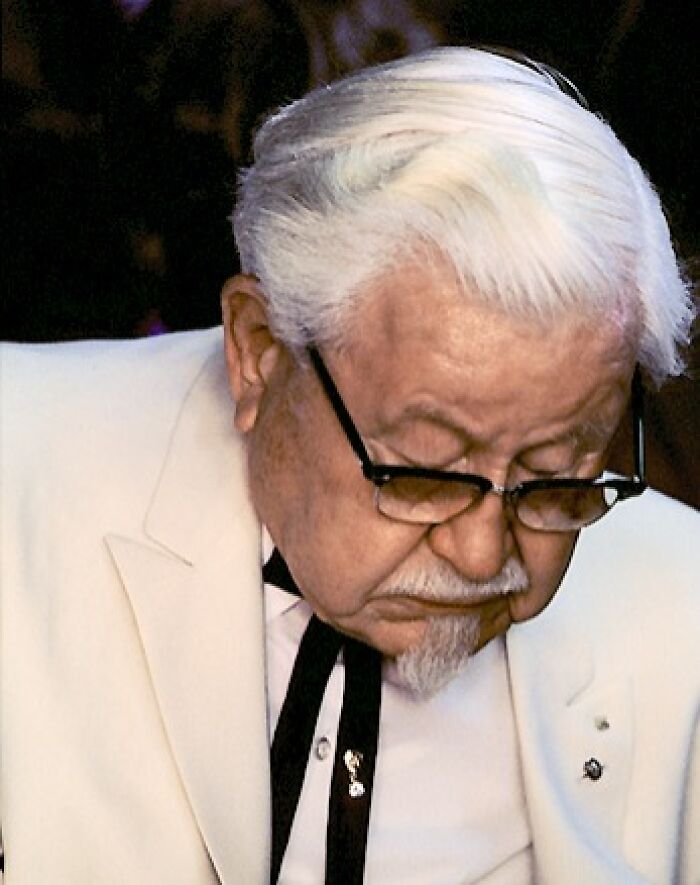 Elderly man with white hair and glasses wearing a white suit, symbolizing late bloomers who became millionaires.