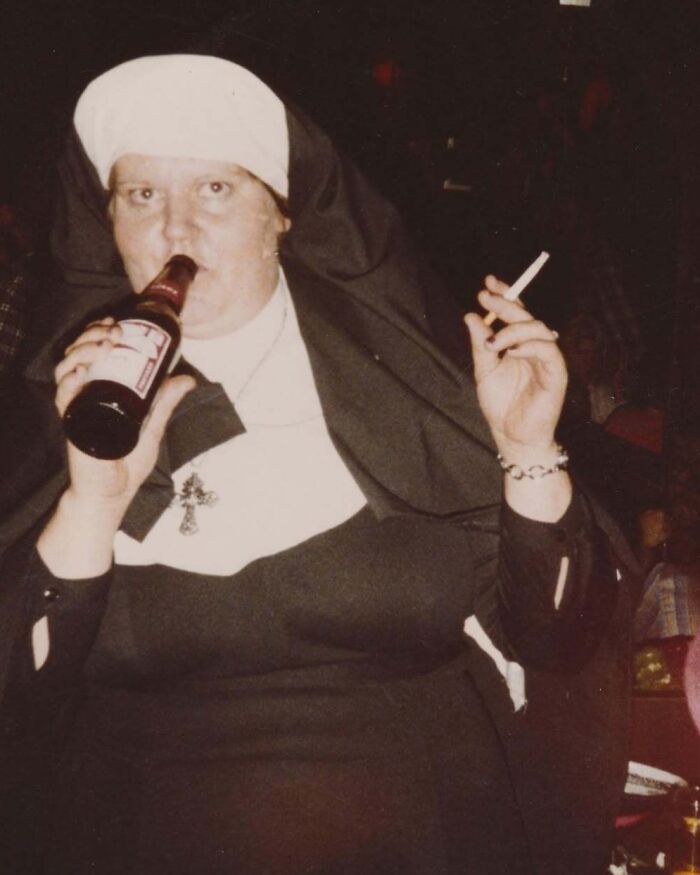 Vintage photo of a nun drinking beer and smoking a cigarette in a casual, unexpected moment from history.