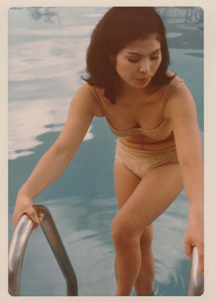 Vintage photo of a woman in a 1960s swimsuit climbing out of a pool, showcasing captivating vintage moments in history.