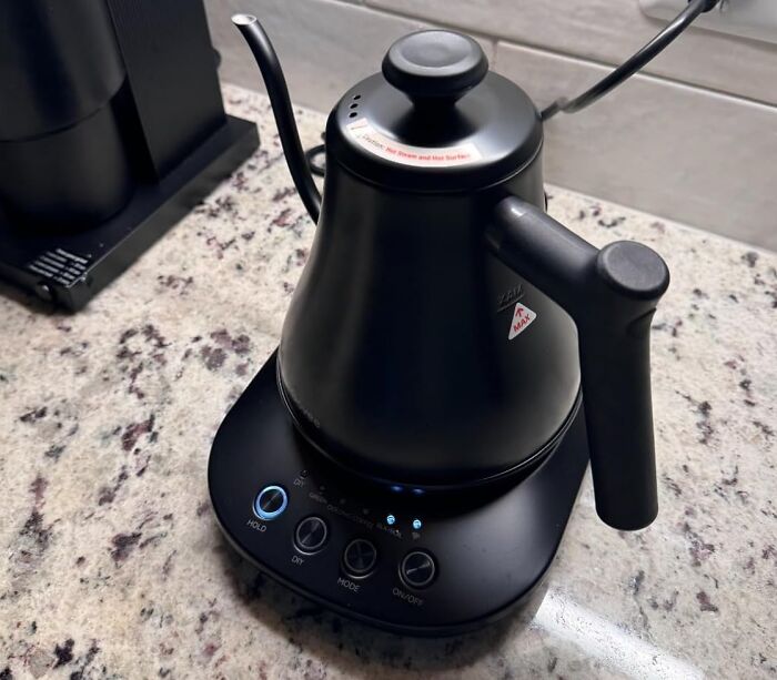 Matte black electric kettle with digital controls on a granite countertop, example of unusual kitchen gadgets.