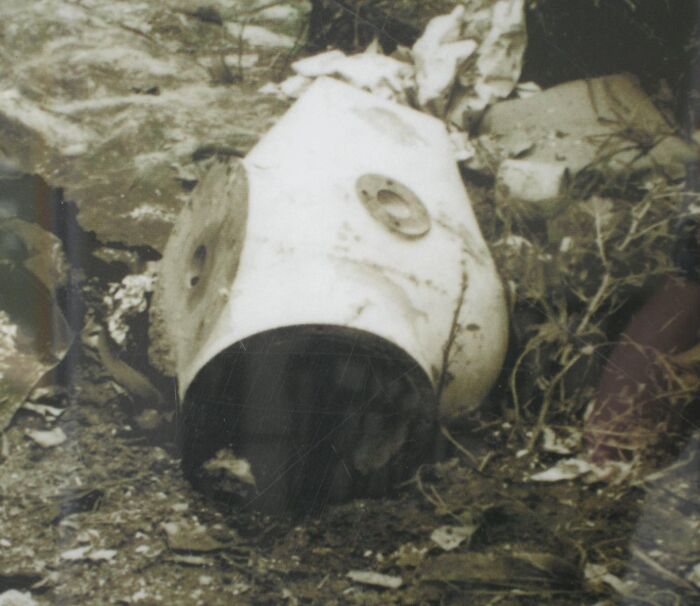 Old, worn helmet lying discarded in dirt and debris, evoking eerie and unsettling Wikipedia article moments.