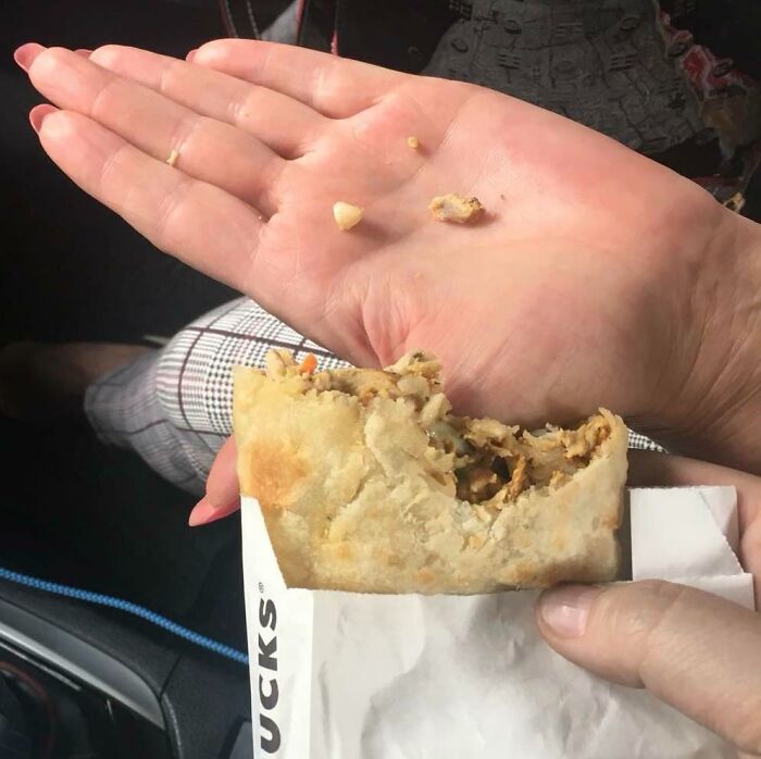 Partially eaten burrito with filling falling onto a parent's palm, capturing a hilariously unlucky moment for parents.