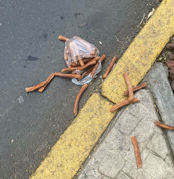 Unlucky parents' spilled snacks on the street near a yellow curb showing a small parenting mishap outdoors.