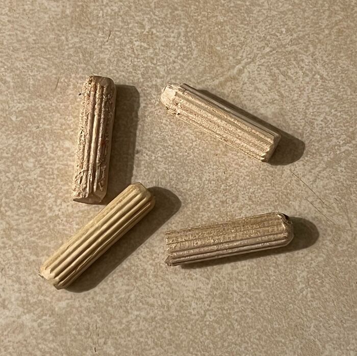 Piezas de madera desgastadas sobre superficie clara representando momentos difíciles de padres y madres.