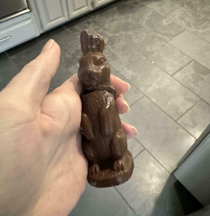 Figura de chocolate con partes rotas en la mano de un adulto, ejemplificando un día peor para padres y madres.