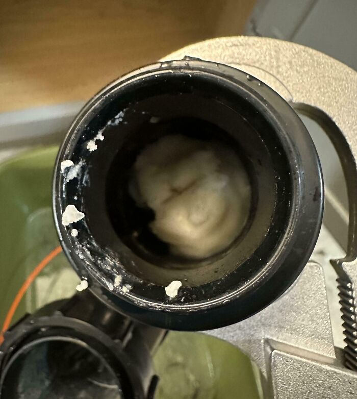 Residuo blanco acumulado en tubería de desagüe, mostrando problema doméstico común para padres y madres.