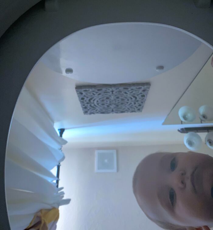 Bebé curioso mirando al espejo en una escena cotidiana de padres y madres teniendo un día peor que el tuyo.