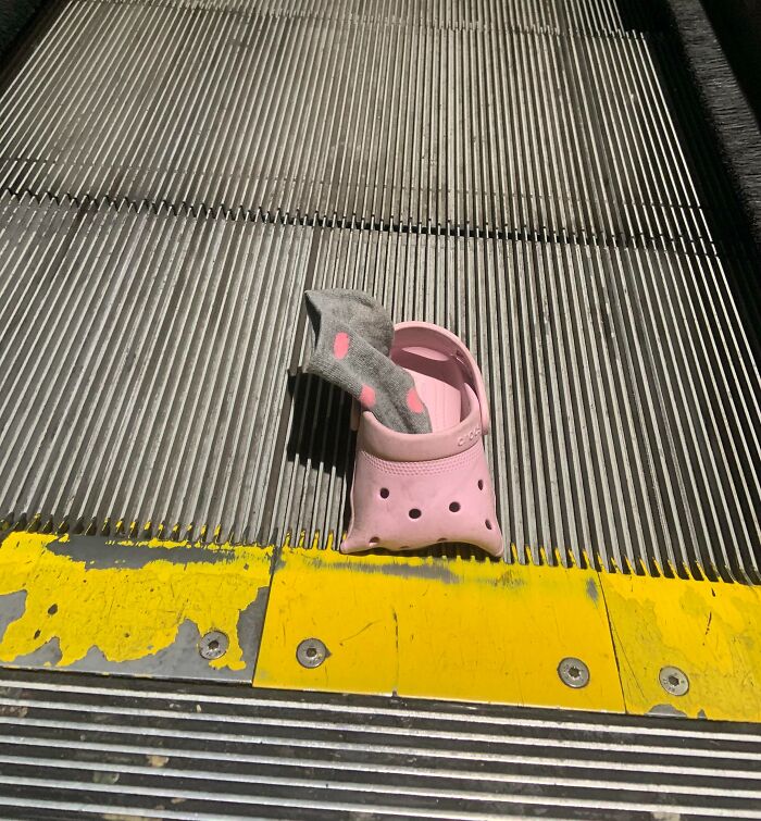 Zapato rosado con calcetín gris atrapado en una escalera mecánica, mostrando un día peor para padres y madres.