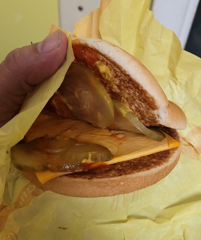 Partially assembled cheeseburger with pickles and sauce, illustrating hilariously unlucky parents' meal fail.