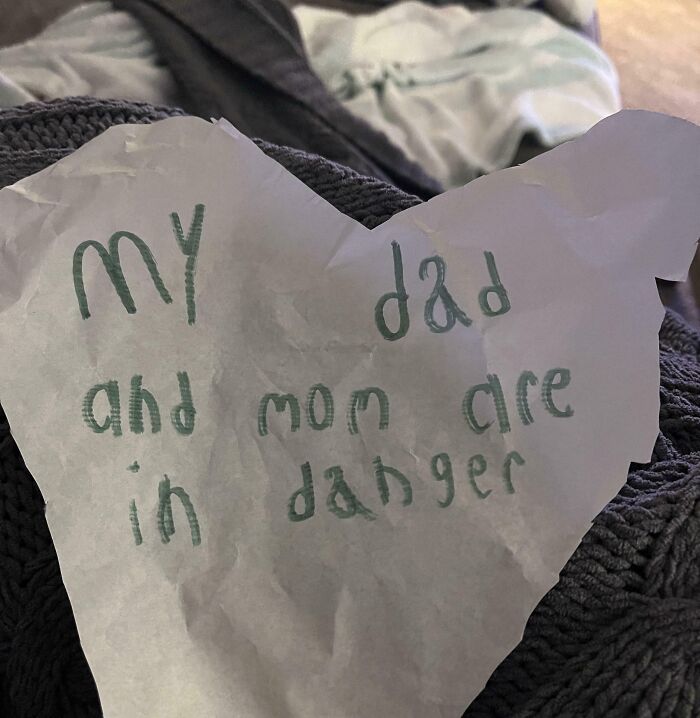 Child's handwritten note on crumpled paper saying my dad and mom are in danger, a funny unlucky parents moment.