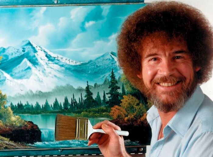 Painter smiling while holding a brush in front of a mountain landscape, representing late bloomers becoming millionaires.