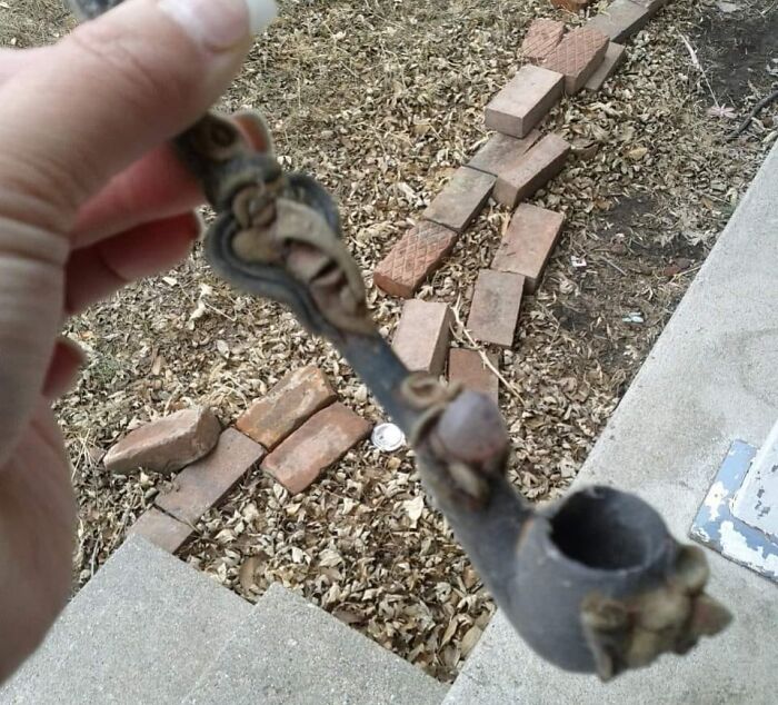 Hand holding an old, decorative pipe found among unexpected things hidden in walls and other home places.