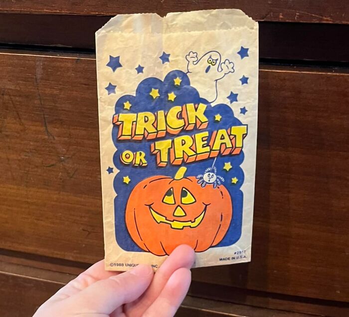 Hand holding a vintage Trick or Treat bag found as an unexpected item in walls and hidden places in homes.
