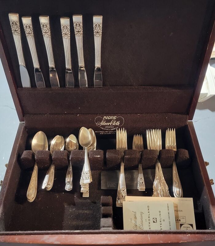 Silverware set found hidden in walls and other unexpected places in people’s homes, displayed neatly in a wooden box.