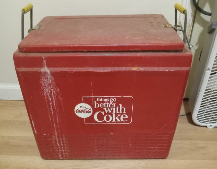 Red vintage Coca-Cola cooler placed on a wooden floor, representing unexpected things found in walls and hidden places.