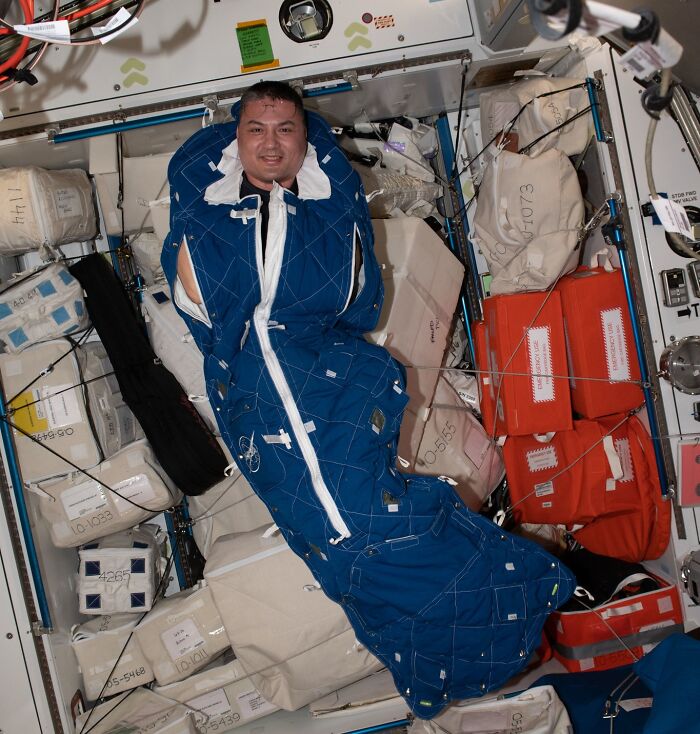 Astronaut floating inside spacecraft surrounded by storage bags and equipment, illustrating intriguing astronaut facts in space.