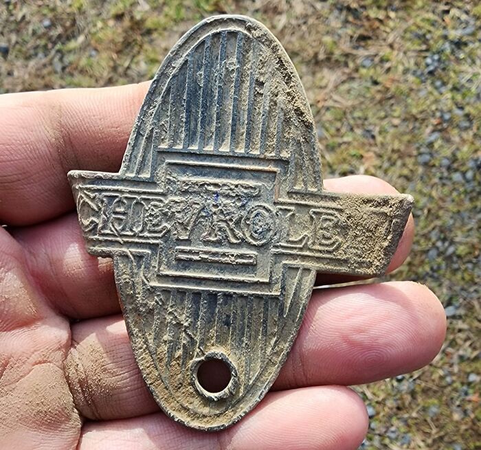 Hand holding a dusty vintage Chevrolet emblem uncovered from walls and other hidden places in people’s homes.