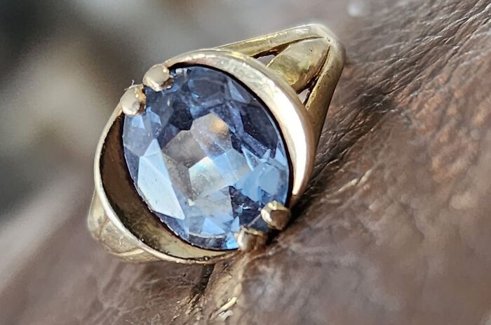 Close-up of a gold ring with a blue gemstone, one of the unexpected things found in walls and hidden places in homes.
