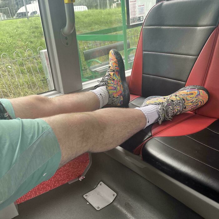 Passenger with colorful sneakers resting feet on public transport seat, showing infuriating behavior of some passengers.