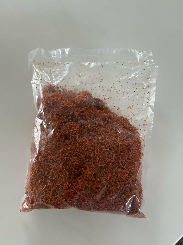 Clear plastic bag filled with shredded reddish-brown mystery object placed on a white surface for recognition.
