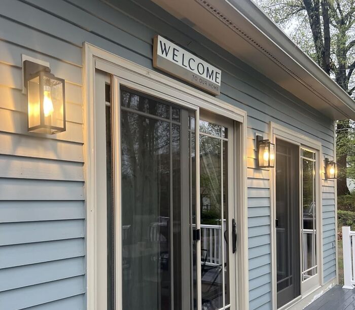Outdoor wall lights illuminating a porch area with sliding glass doors, enhancing usability of outdoor space after dark.