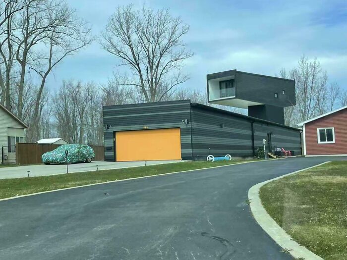 Modern black house with an unusual cantilevered design and a camouflaged car, an interesting thing to double take and realize.