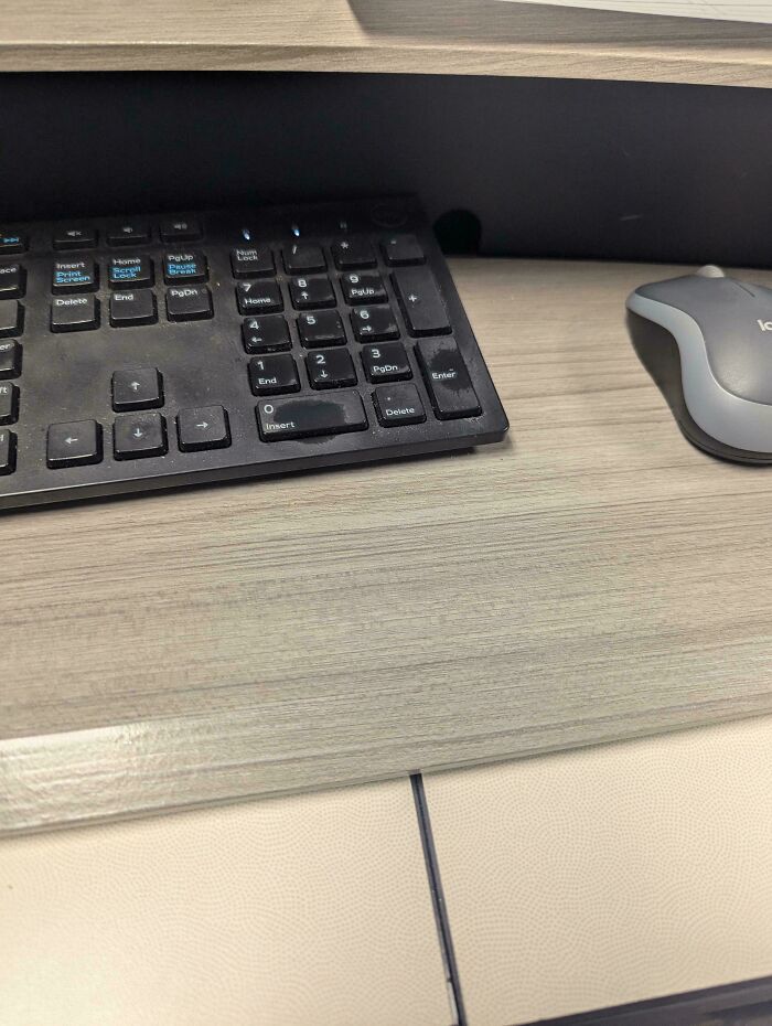 Dusty black keyboard and gray mouse on a wooden desk in an extremely toxic work environment captured by employees.