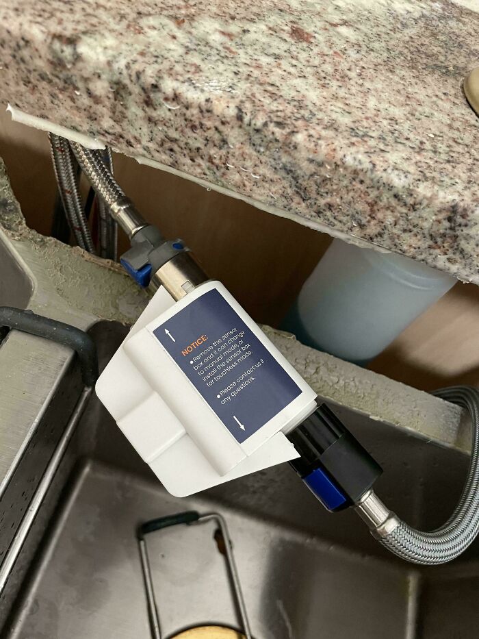 Under-sink plumbing with an attached white sensor device, part of a mystery object helping online group recognition.
