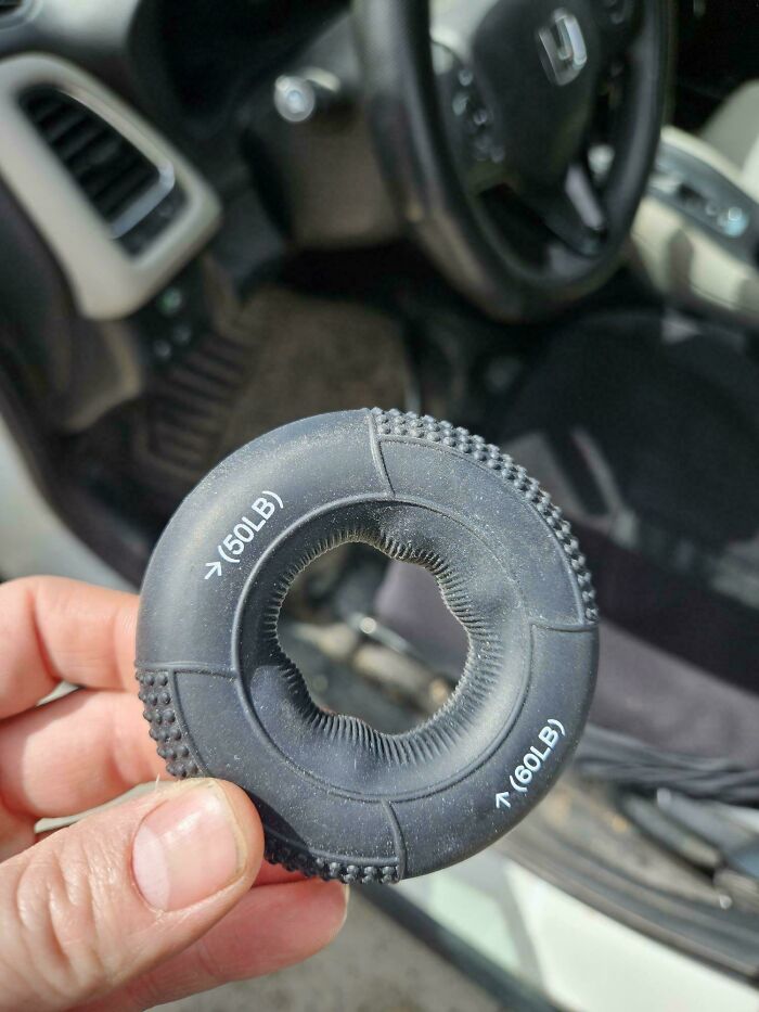 Hand holding a mystery object with textured grips and weight markings, part of a collection of recognized mystery objects.