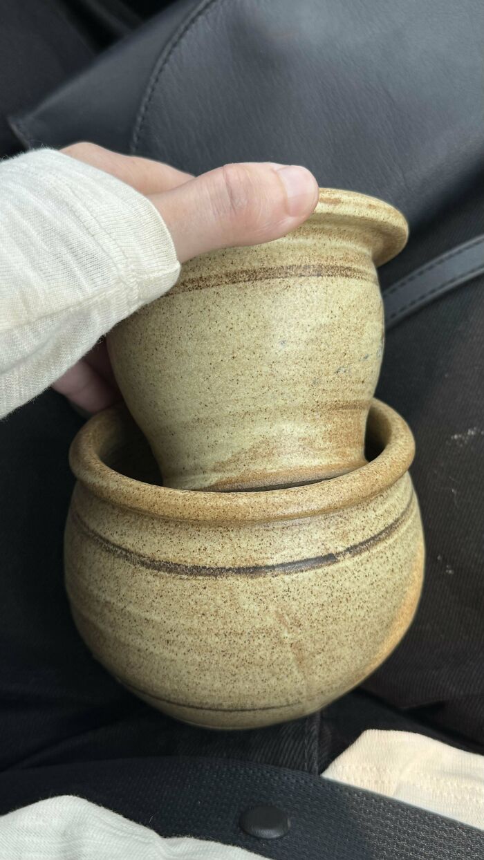 Hand holding two beige pottery pieces with horizontal stripes, part of a collection of mystery objects recognized online.