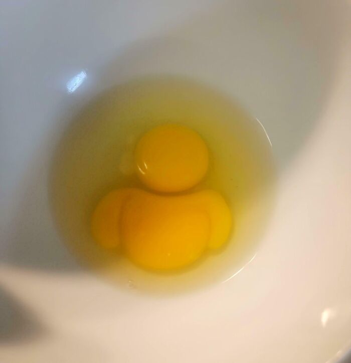 Close-up of an egg yolk in a bowl shaped like a person, an interesting thing requiring a double take to realize what it is.