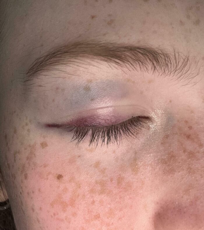 Close-up of a freckled closed eye with subtle makeup showing interesting details that require a double take.