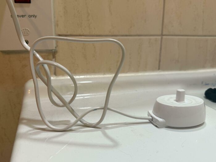 White electric cord twisted into a shape on a bathroom counter, an interesting thing requiring a double take to realize.