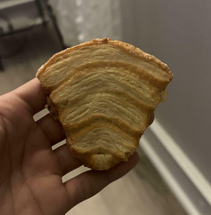 Hand holding a pastry that looks like an unusual layered object, an interesting thing requiring a double take to realize.