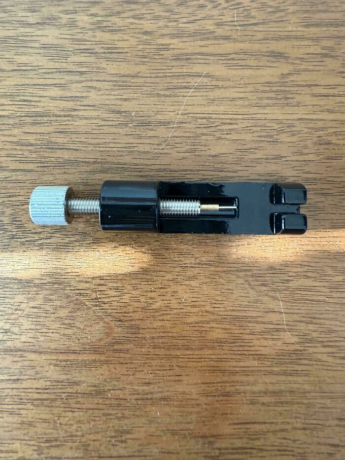 Black adjustable metal tool with s***w mechanism on wooden surface for recognizing mystery objects online.