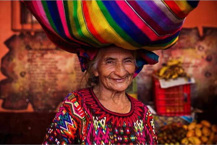 Elderly woman from Guatemala wearing colorful traditional clothing and smiling, showcasing beauty without expiration date.