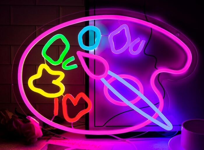 Neon light art shaped like a painter’s palette and brush glowing in vibrant colors for creative spirit inspiration.