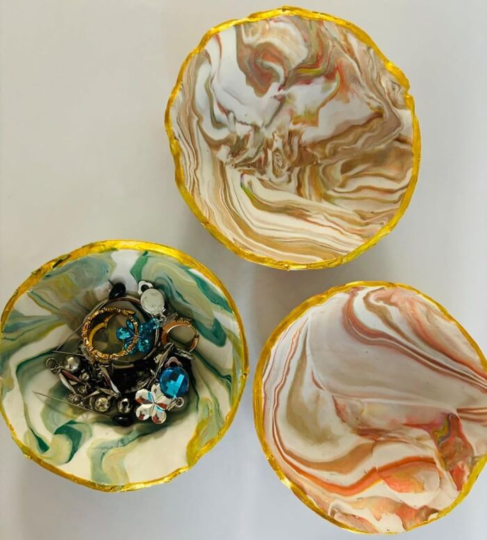 Three marbled decorative bowls with gold edges, one holding assorted jewelry, showcasing creative arty finds.