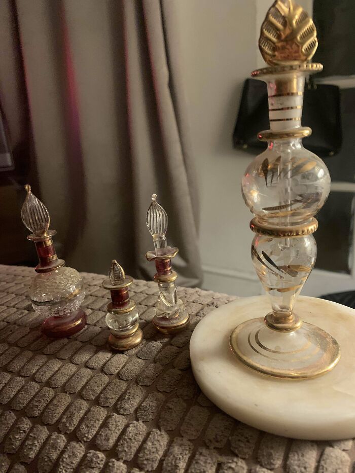 Set of four ornate vintage glass mystery objects with gold accents displayed on a textured surface in home setting.