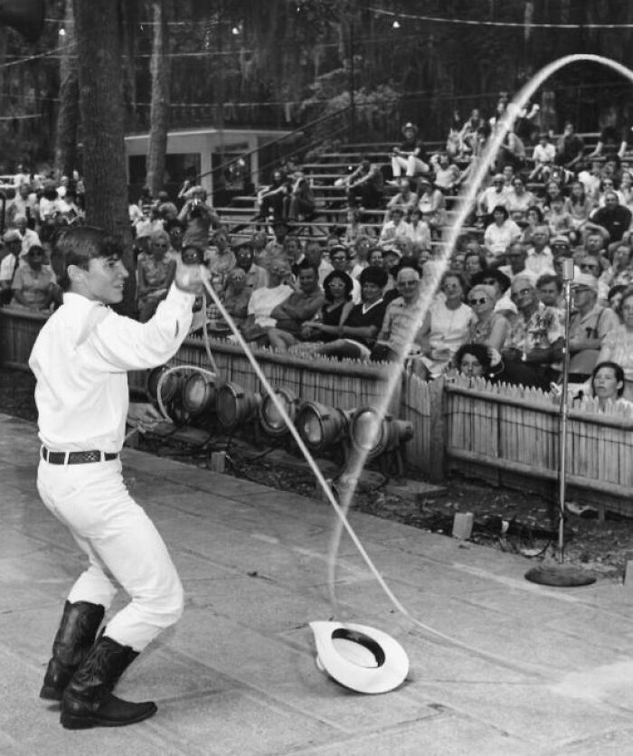 Young cowboy performing a vintage lasso trick in front of an audience, capturing the spirit of the wild west.