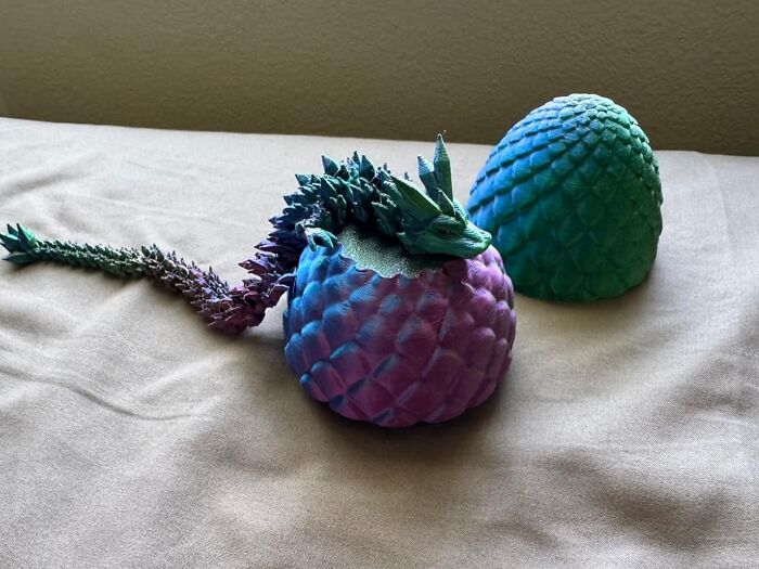 Colorful dragon figurine emerging from a textured egg shell, showcasing creative spirit in unique arty finds.