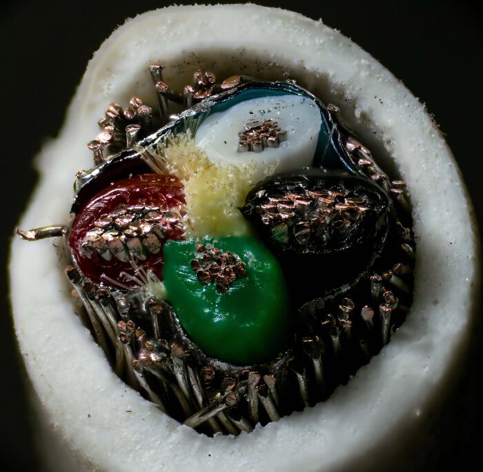Close-up microscopic image of a colorful, multi-strand cable showing intricate copper wiring details and insulation layers.