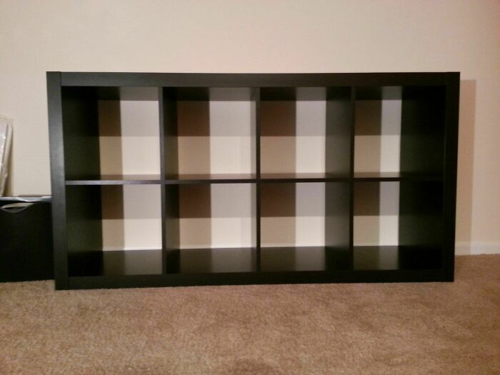 Black shelf casting cool geometric shadows on a wall and carpet, creating an interesting shadow pattern effect.